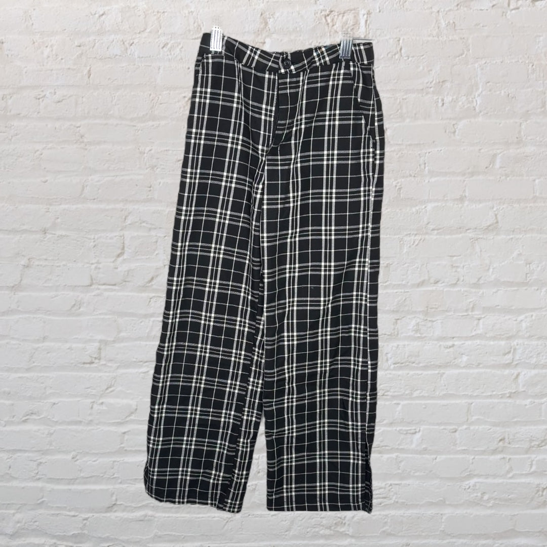 Black and white plaid trousers hanging against a white brick wall.
