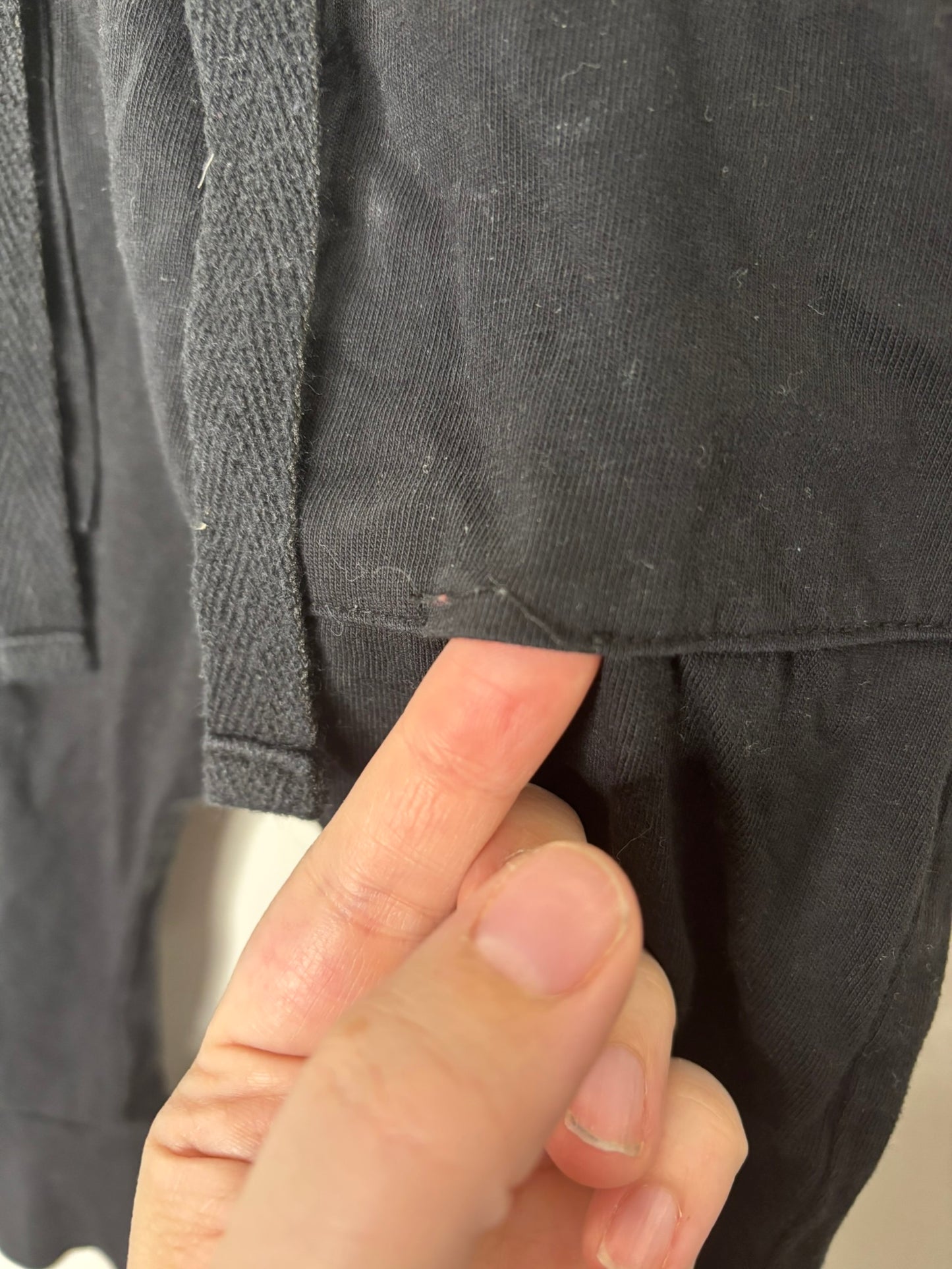 Children's black jogger pants with drawstring waist displayed on a hanger against a white brick background.