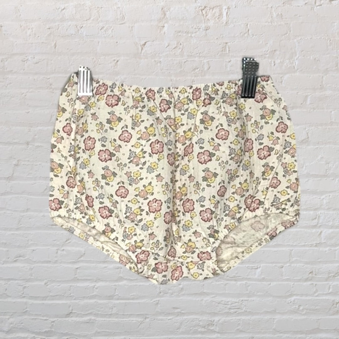 Cream floral dress with ruffle straps and lace trim, featuring pink and yellow flowers, hanging on a hanger.