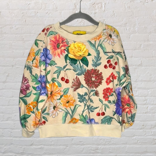 Multicolour floral patterned sweater with crewneck design by Maison Meugsten, hanging on a hanger against a white brick wall.