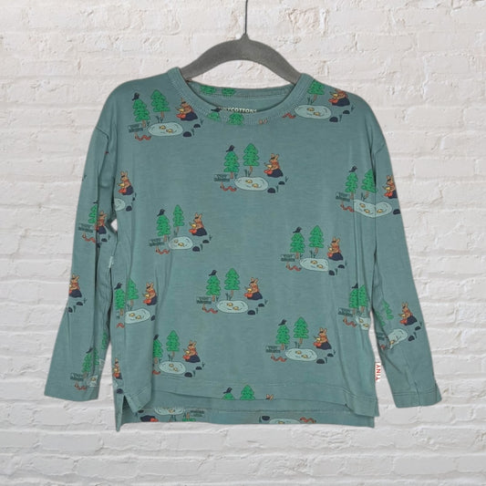 Blue long sleeve shirt with cartoon forest animals and trees, hanging on a hanger.
