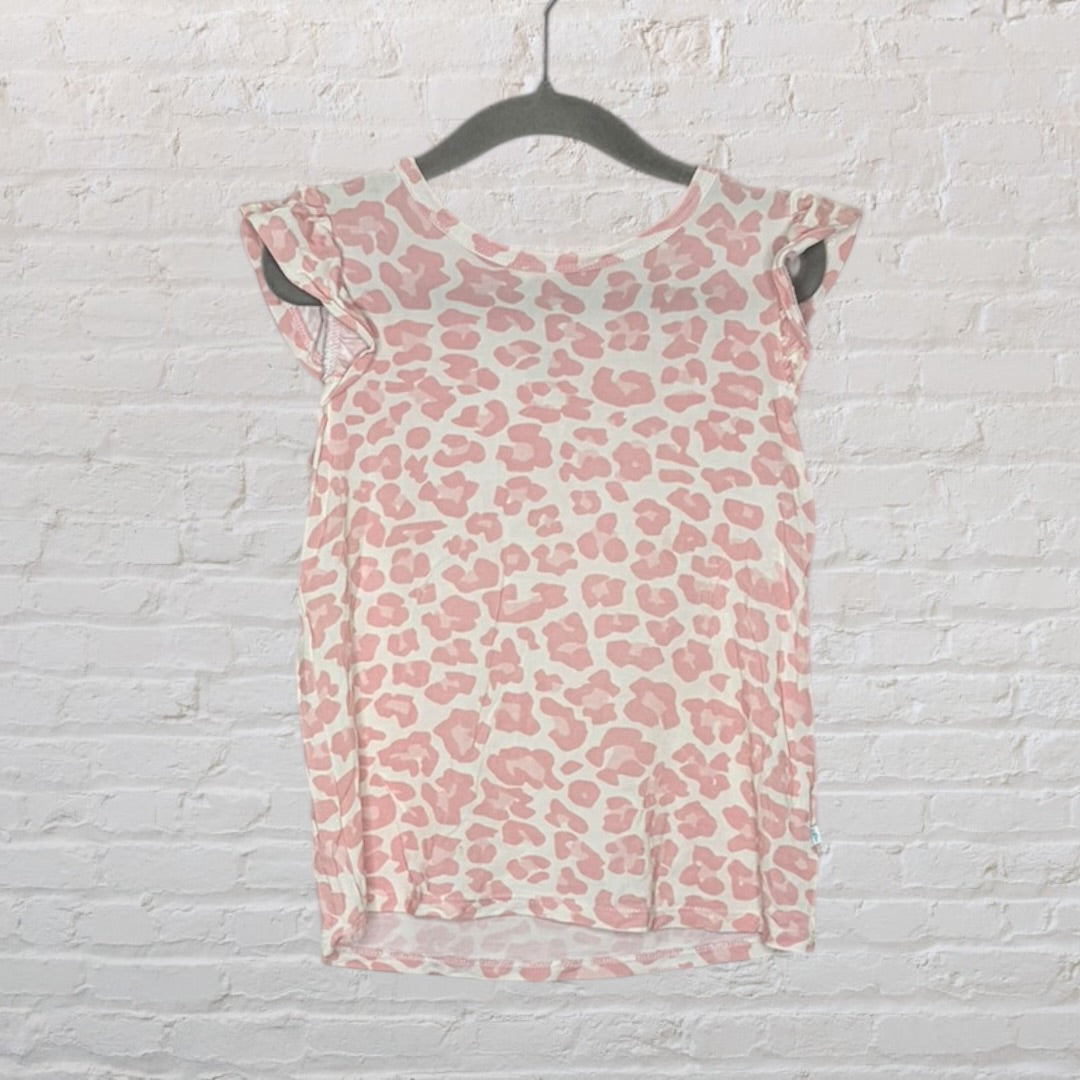 Women's pink leopard print top with cap sleeves, hanging on a black hanger against a white brick wall.