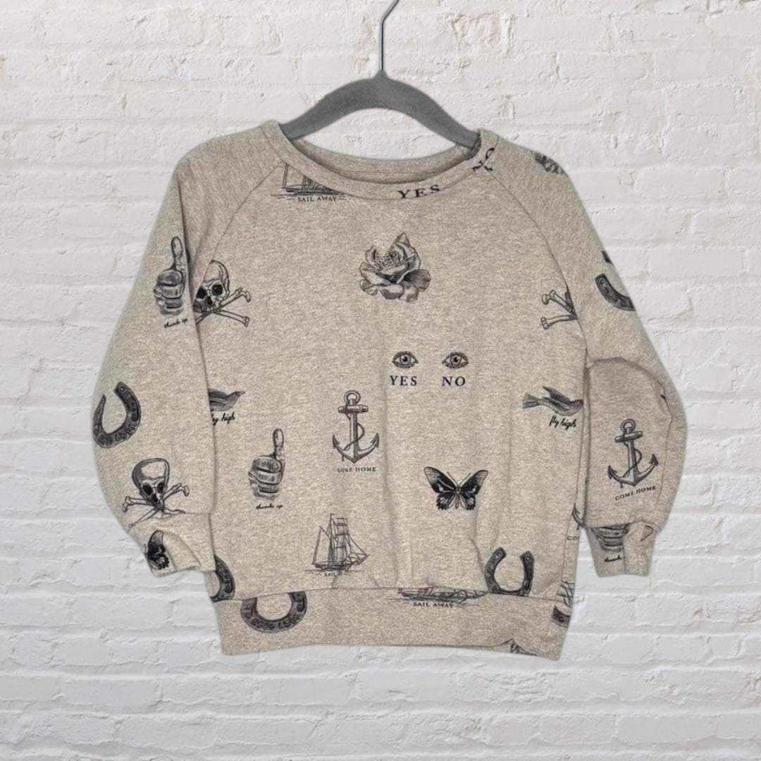 Heather grey sweatshirt with tattoo-inspired graphics including anchors, skulls, and horseshoes, hanging on a hanger.