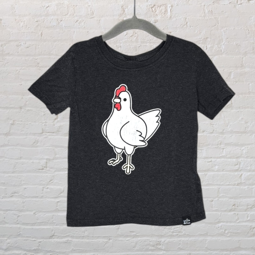 Dark gray T-shirt with a cartoon chicken graphic displayed on a hanger against a white brick wall.