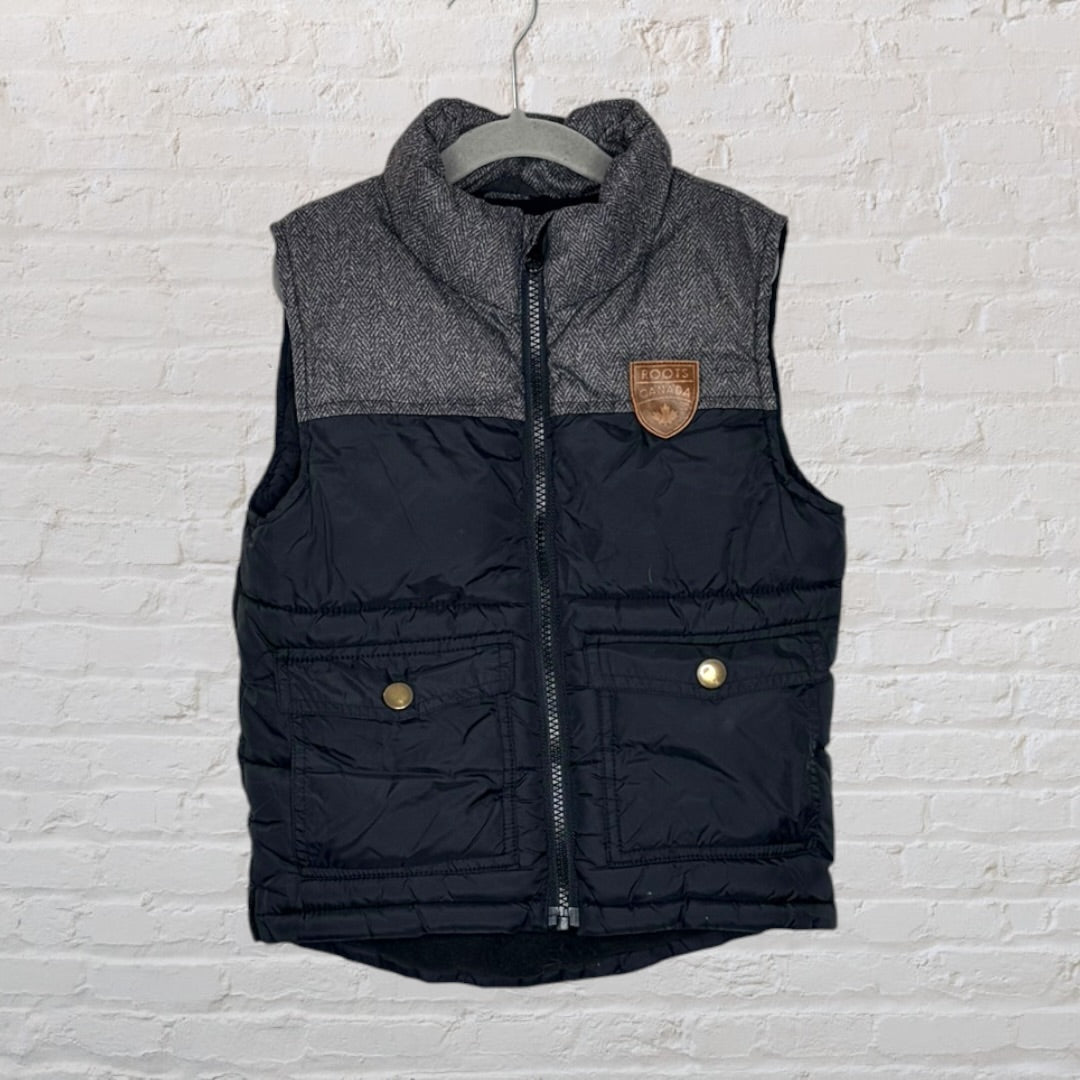 Black and grey quilted vest with tweed accents and a Roots Canada leather patch, featuring front pockets and a zip closure.
