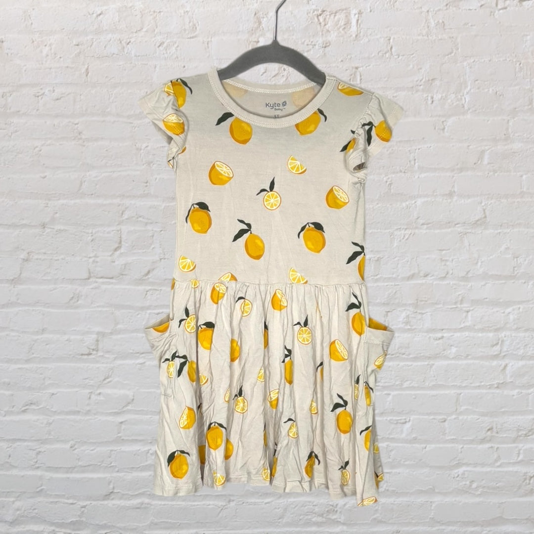 Cream dress with yellow lemon print and pockets, displayed on a hanger.