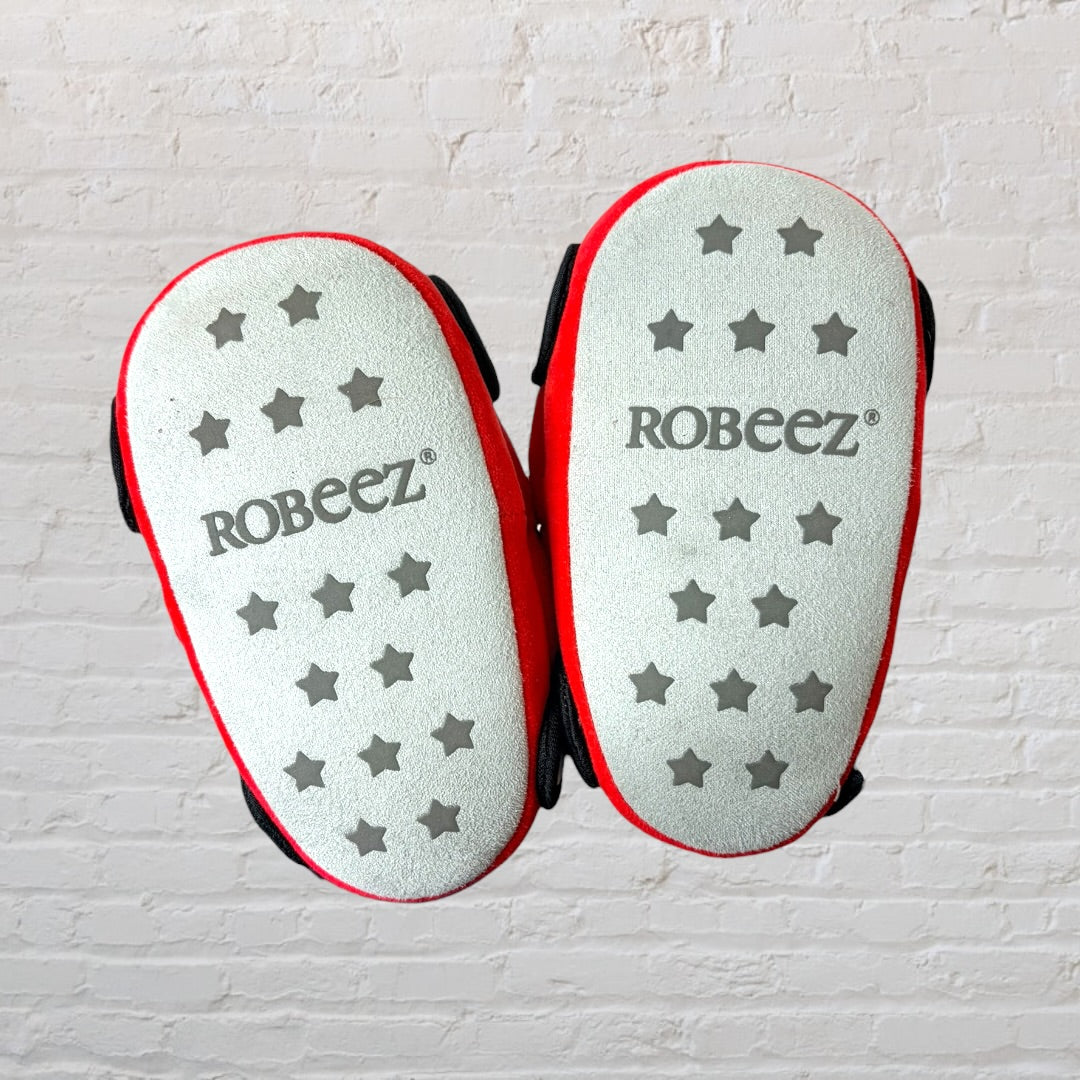 Bright red plush slippers shaped like fire trucks with black wheels and window details.