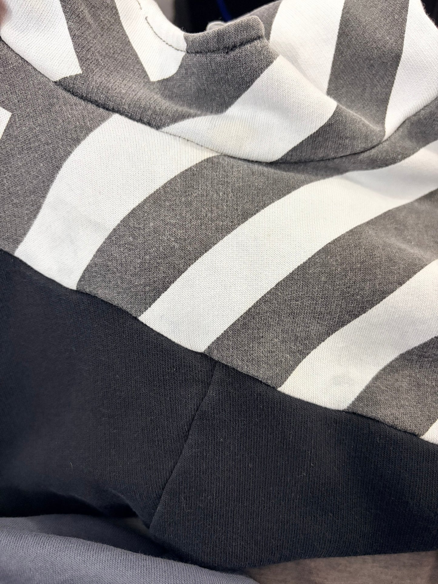 Unisex hoodie with diagonal black and grey stripes and color block design, featuring a cozy hood.