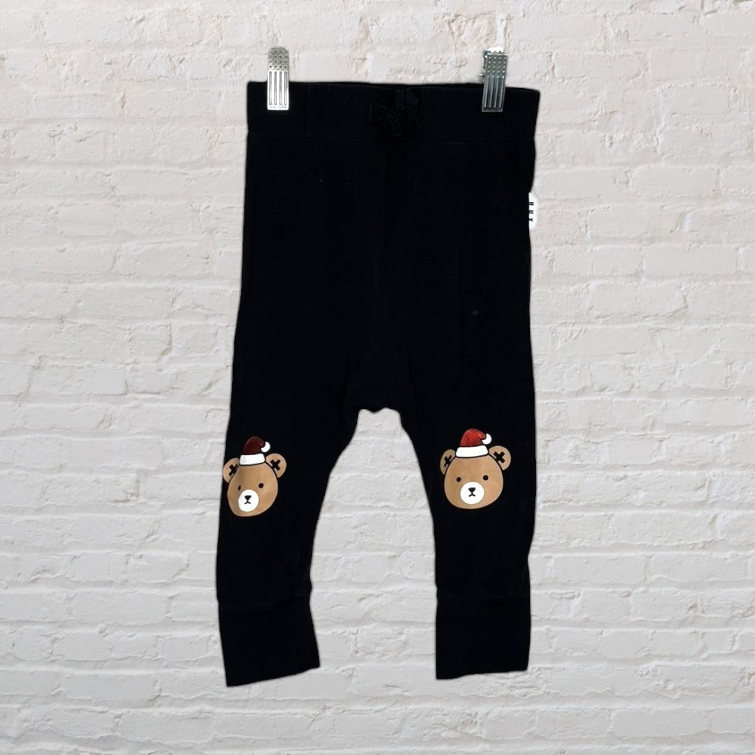 Black leggings with festive bear prints wearing Santa hats, hung against a white brick wall.