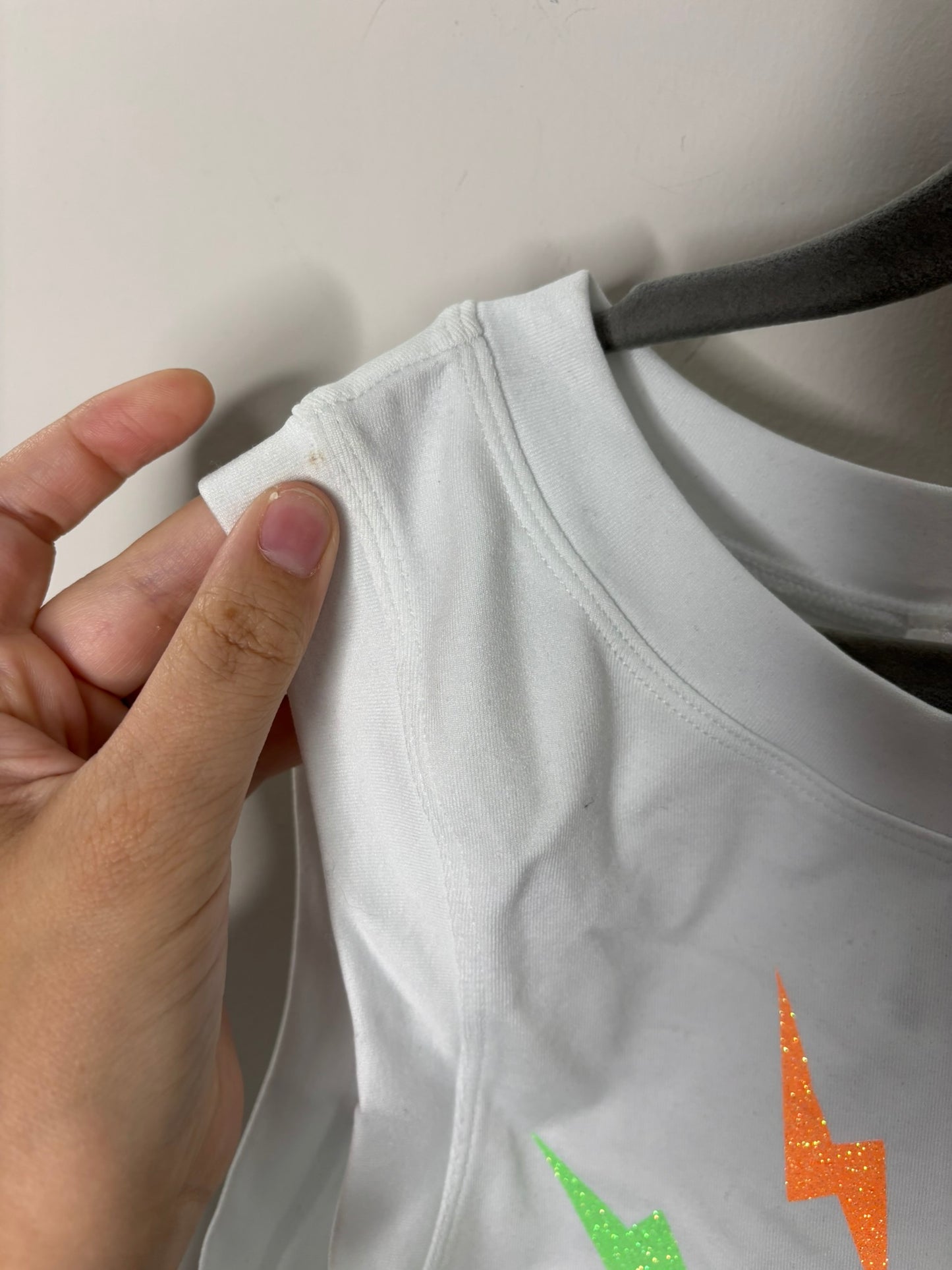 White tank top with colorful lightning bolt graphics and sleeveless design on a black hanger.