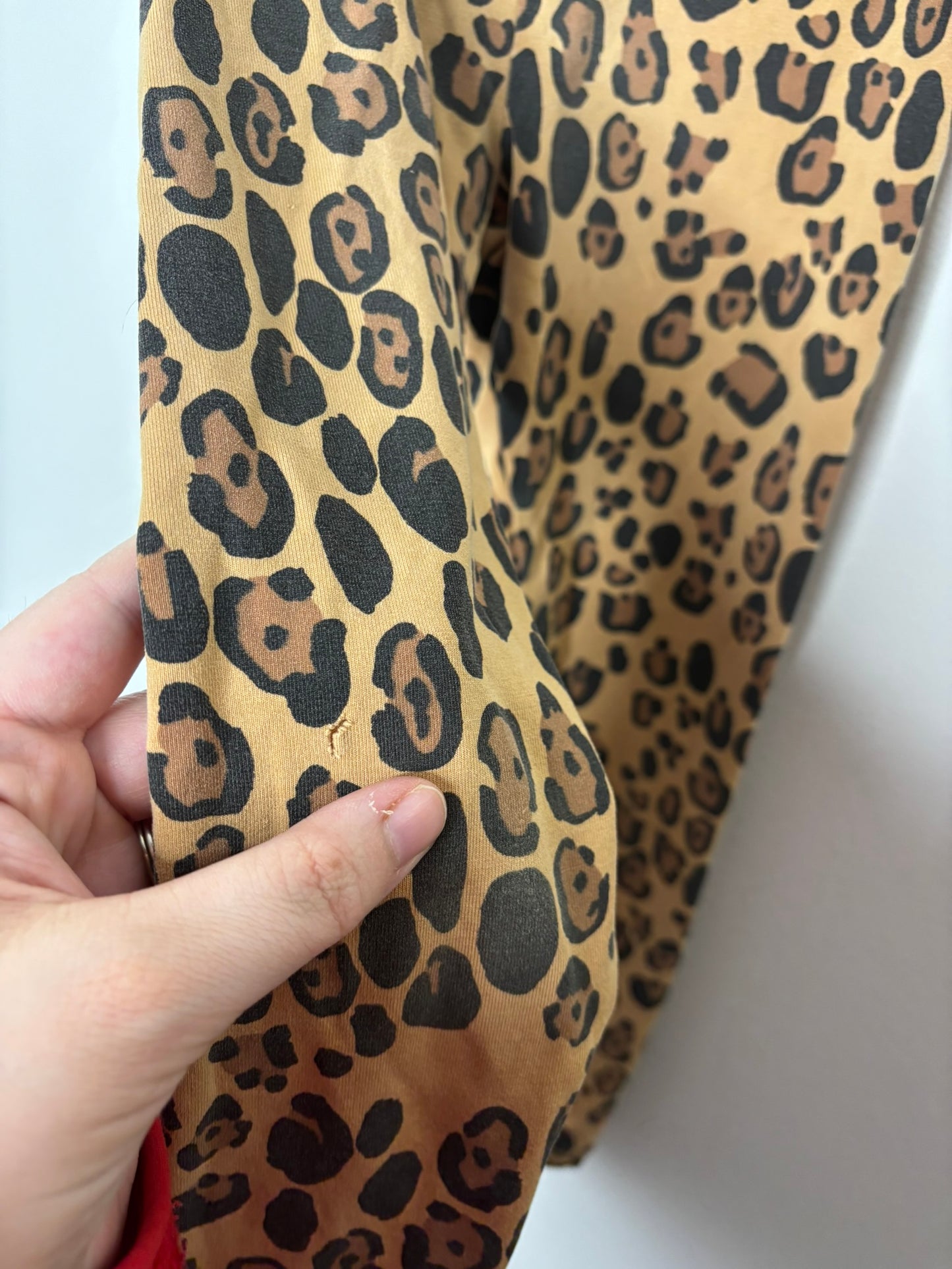 Brown and black leopard print leggings hanging on a white brick background.
