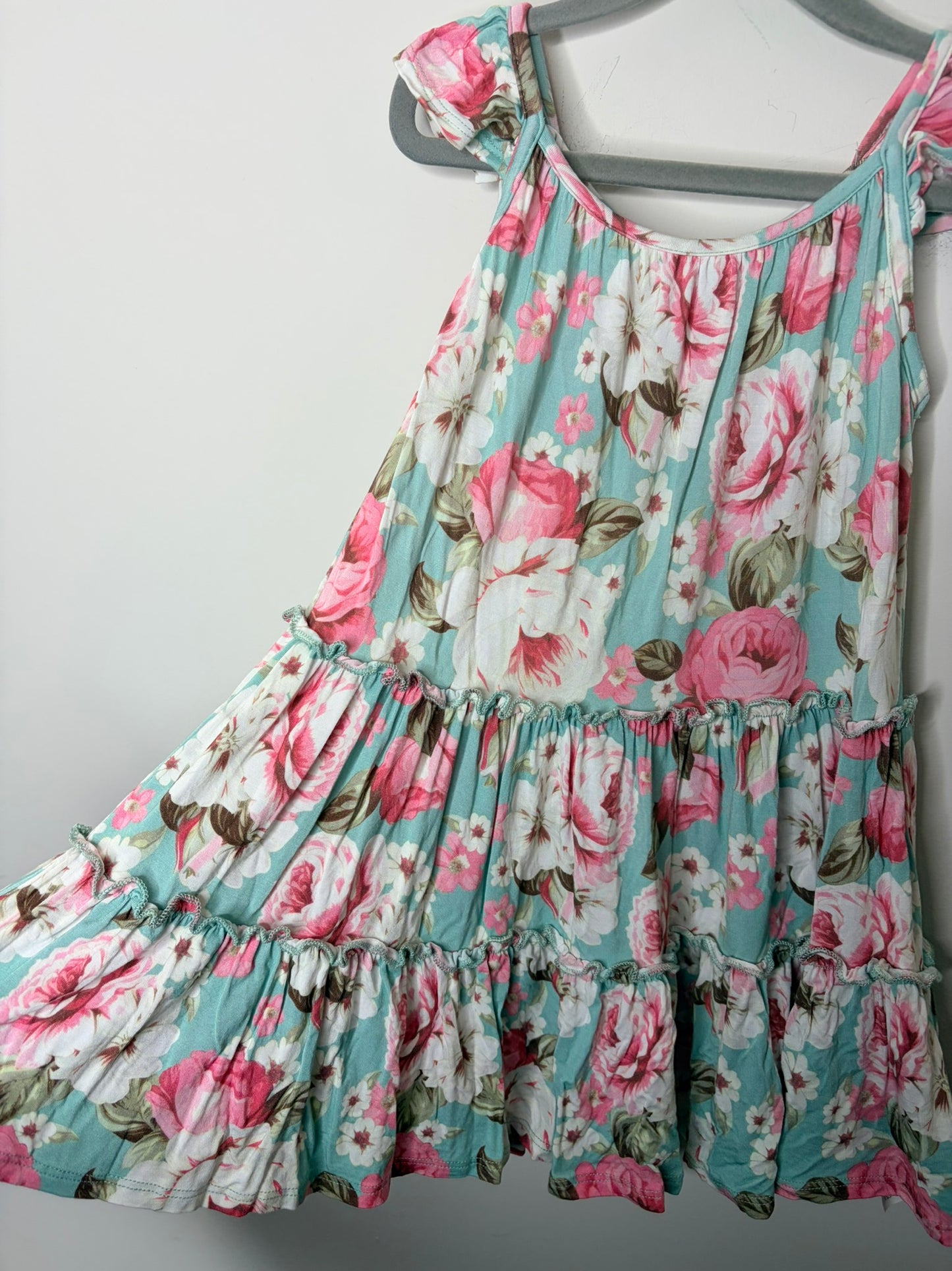 Mint green floral summer dress with pink and white flowers, featuring tie sleeves, hanging on a gray hanger.