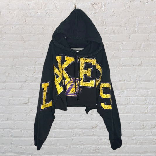 Black cropped hoodie with yellow and purple Lakers logo and text design.
