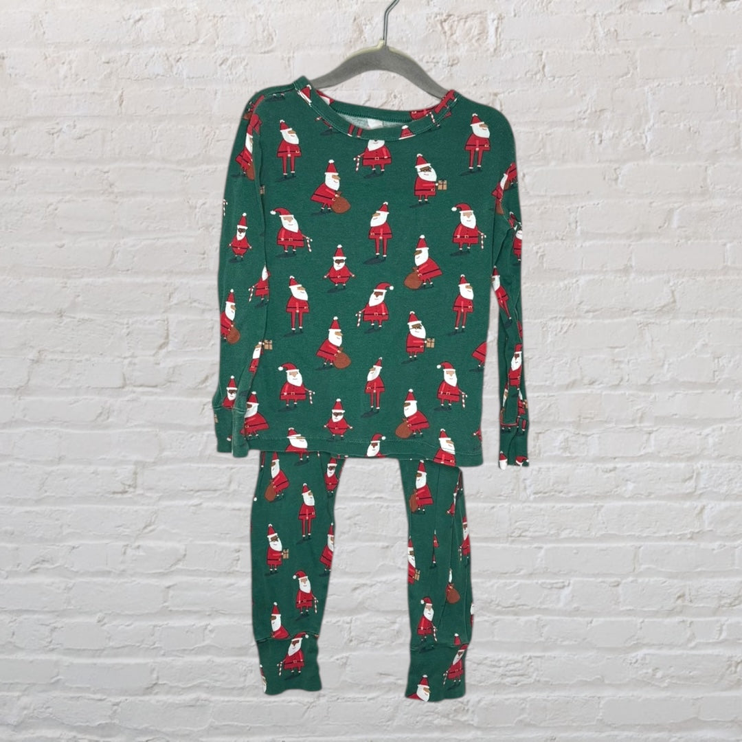 Green pajama set with Santa Claus prints, featuring a long-sleeve top and matching pants, hanging on a hanger.