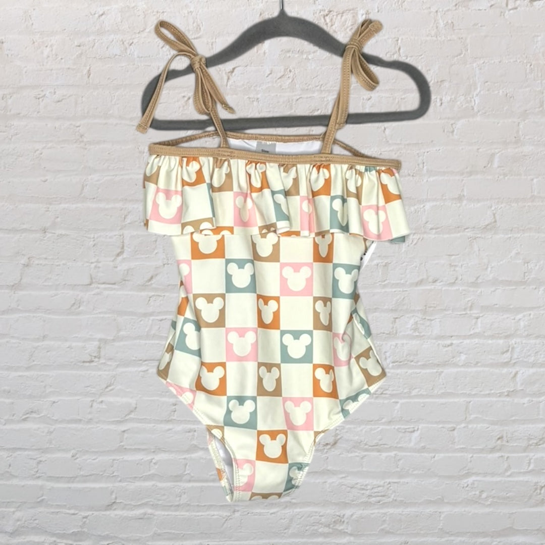 Swimsuit featuring a Mickey Mouse checkerboard pattern with ruffle trim and tie straps in cream and pastel colors.
