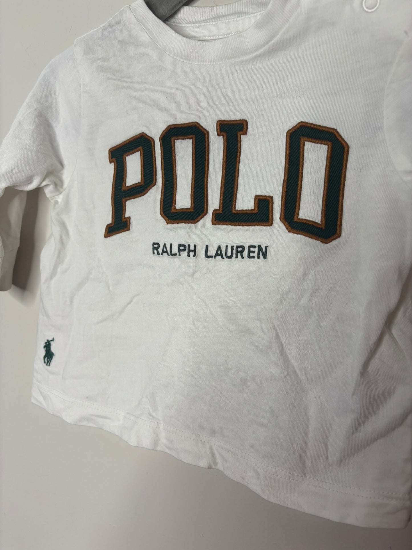 White baby long sleeve top with 'POLO RALPH LAUREN' printed on the front, featuring a side polo player logo.