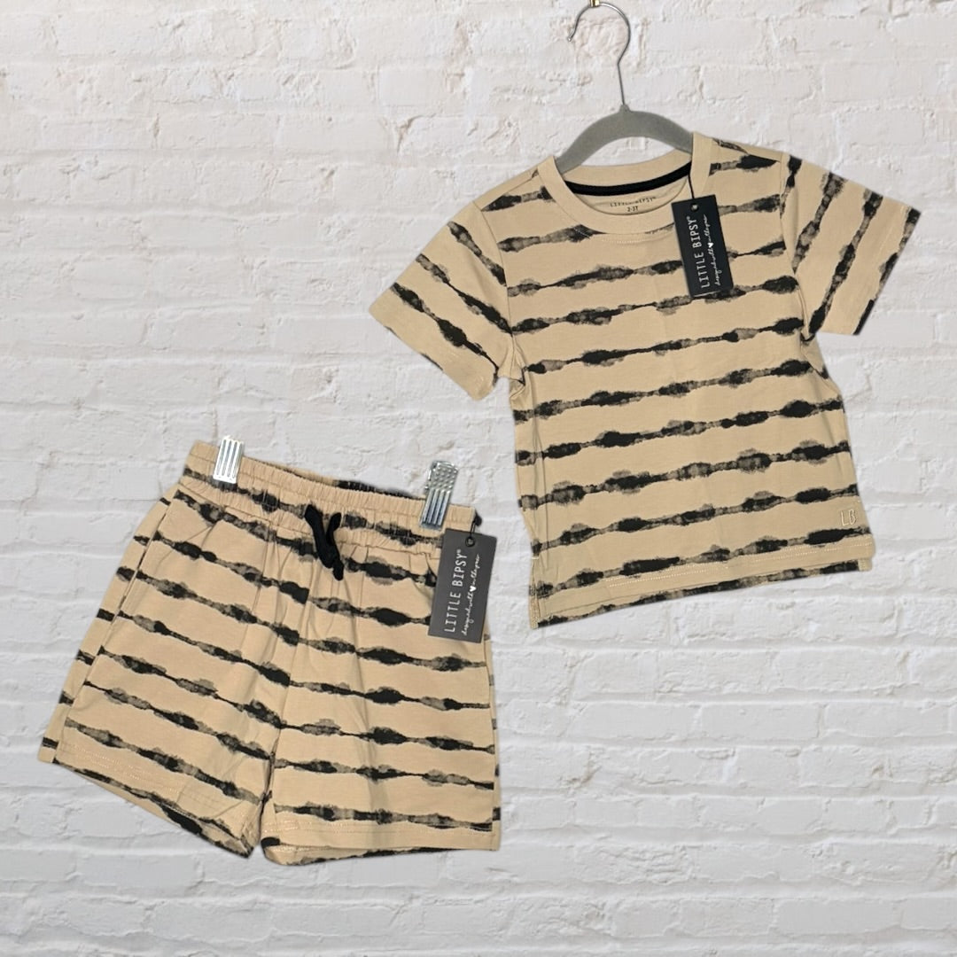Beige and black striped t-shirt and shorts set with tags, by Little Bipsy for kids, displayed against a white brick wall.