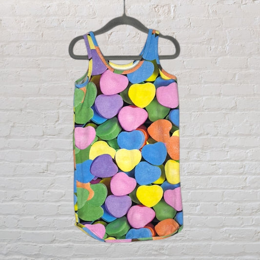 Sleeveless tank dress with a vibrant multicolour heart candy print hanging on a hanger.