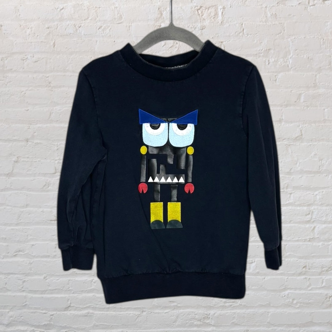 Black long-sleeve sweatshirt featuring a colourful monster graphic with blue, yellow, and red accents, hanging on a hanger.