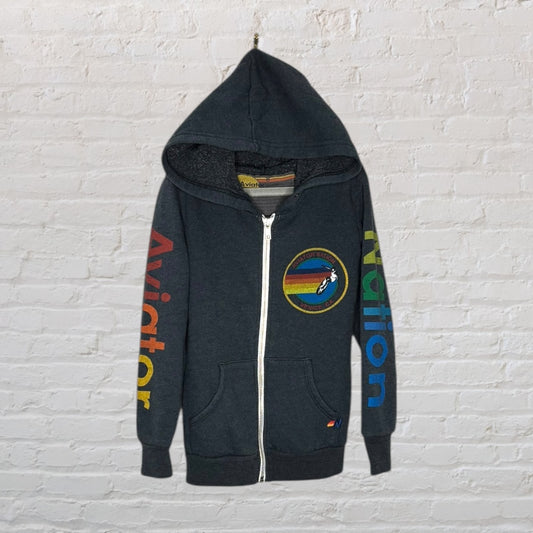 Dark grey Aviator Nation zip-up hoodie with colorful text on the sleeves and a patch on the chest.