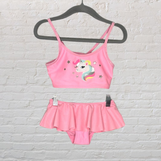 Pink two-piece swimsuit with unicorn graphic, featuring a top and a skirted bottom, displayed on a hanger.