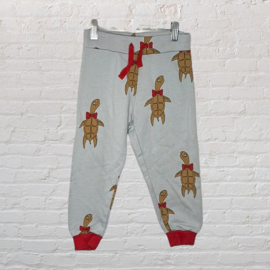Grey jogger pants with turtle print wearing red bows, featuring red waistband and cuffs.