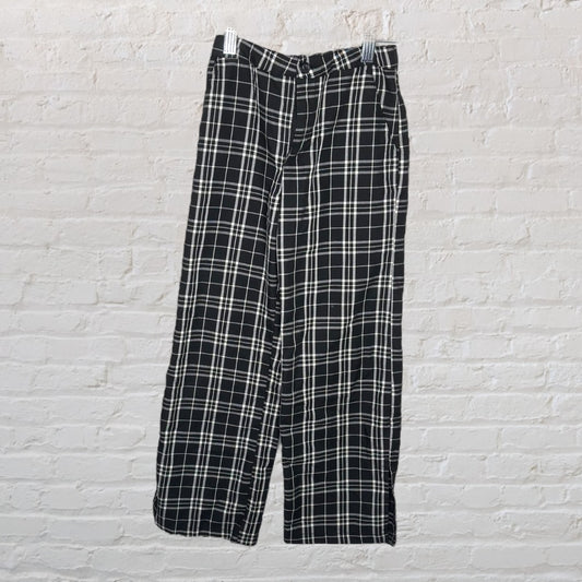 Black and white plaid trousers hanging against a white brick wall.