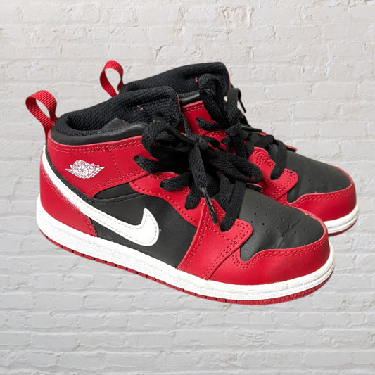 A pair of Air Jordan 1 Retro sneakers in red, black, and white with the iconic swoosh and Wings logo.