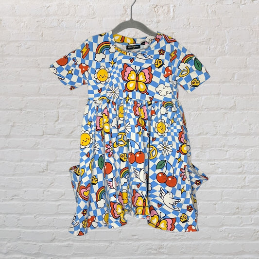 Colorful children's dress with a vibrant all-over print featuring butterflies, rainbows, and cherries, hanging on a hanger.
