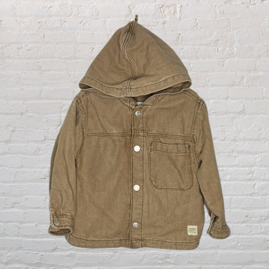 Beige hooded button-up jacket with front pocket, designed for unisex wear.