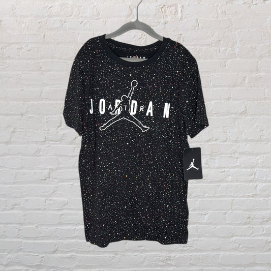 Black Air Jordan T-shirt with multicolored speckles and white logo, hanging on a hanger with tag attached.