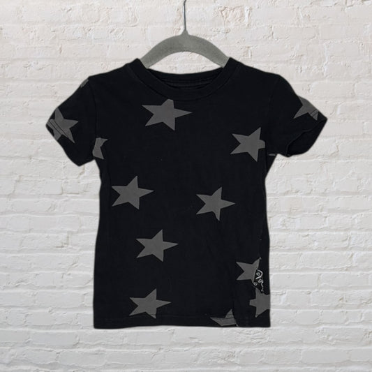 Black T-shirt with grey star pattern, displayed on a hanger against a white brick background.