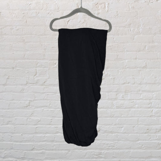 Black maxi skirt on a hanger against a white brick wall background.