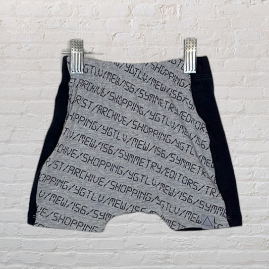 Grey and black shorts with text print hanging against a white brick wall.