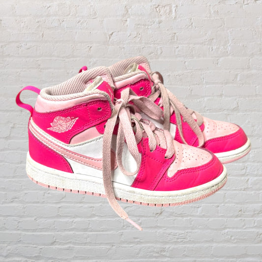 Pair of vibrant pink and white high-top sneakers with laces, displayed against a brick wall.