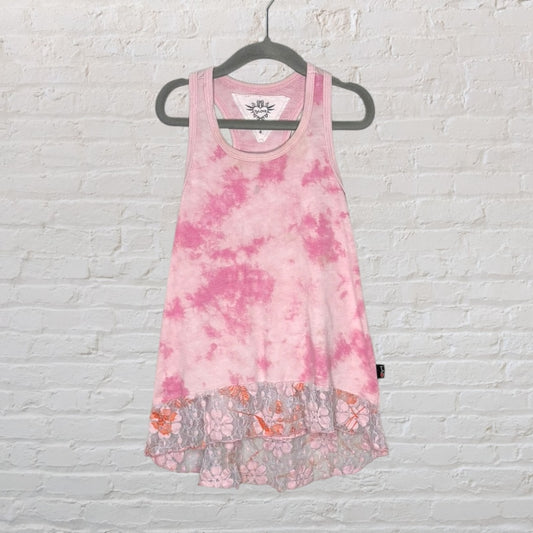 Pink tie-dye tank top with lace hem detail, hanging on a black hanger against a white brick wall.