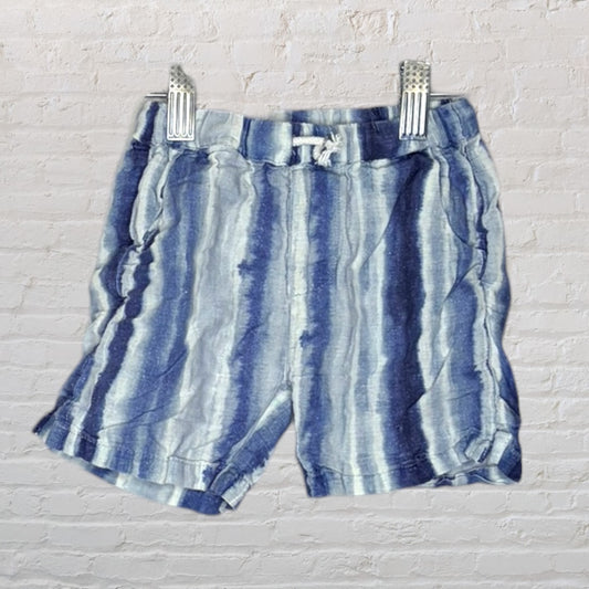 Blue and white tie-dye striped shorts hanging against a brick wall background.