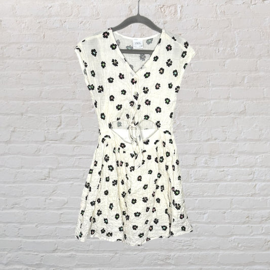 White floral button-down dress with a tie-front detail, sleeveless with a V-neck, hanging on a hanger.