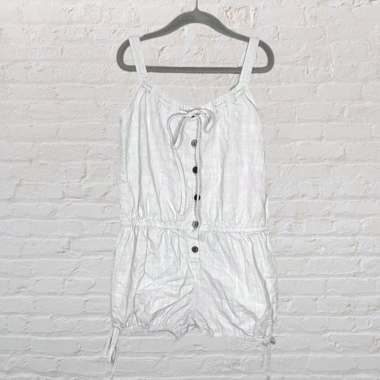 White linen romper with button-up front and adjustable straps, displayed on a hanger.