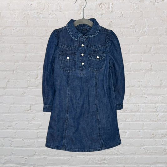 A blue denim dress with button-front closures and long sleeves, featuring two chest pockets.