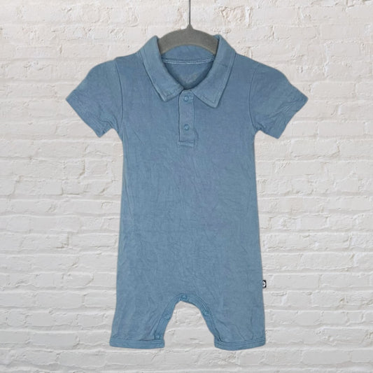Light blue short sleeve polo romper with button closure, hanging on a hanger against a white brick wall.