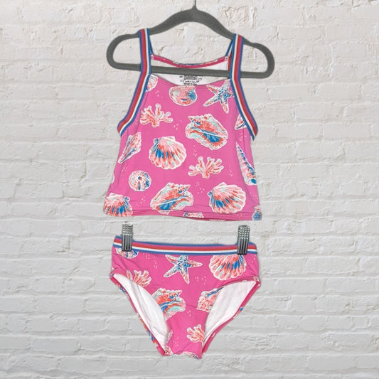 Pink two-piece swimsuit with seashell and ocean-themed prints, featuring blue and red striped edges, displayed on a hanger.