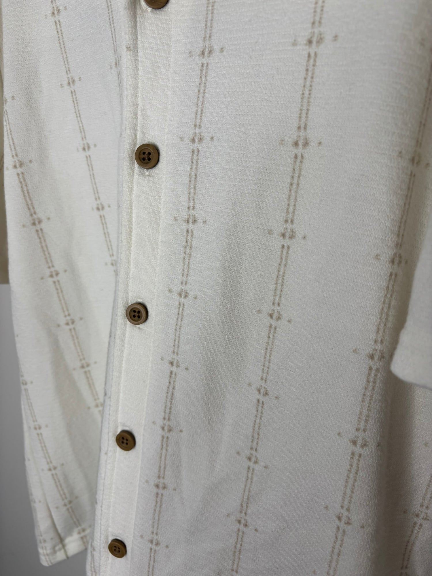 Off-white short sleeve button-up shirt with textured pattern, displayed on a hanger.