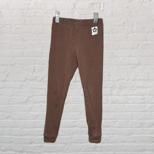 Brown corduroy leggings with a panda tag, displayed against a white brick wall.