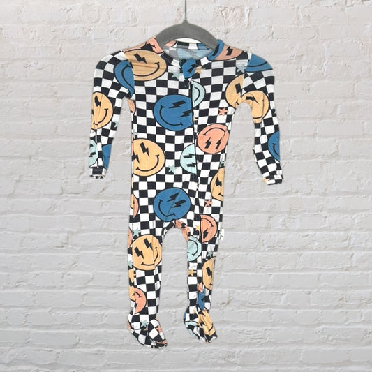 Footed onesie with black and white checkerboard pattern and multicolour smiley faces hanging on a hanger.