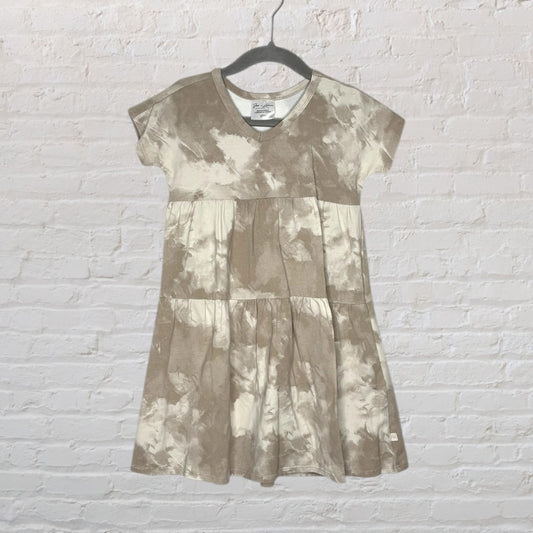 Beige and cream tie-dye V-neck tiered dress hanging on a black hanger.