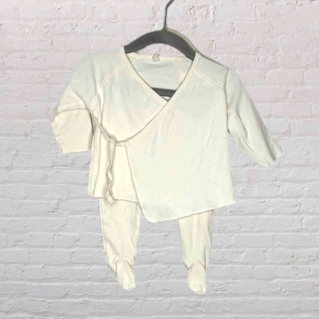 Cream-colored baby outfit with a kimono-style top and footed pants, displayed on a hanger.