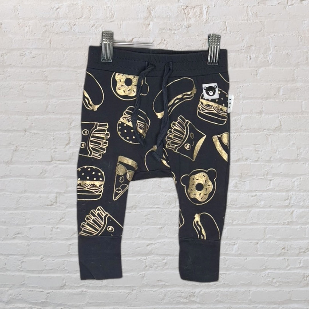 Black baby jogger pants with gold food print, including fries, burgers, and donuts, hanging on clips.