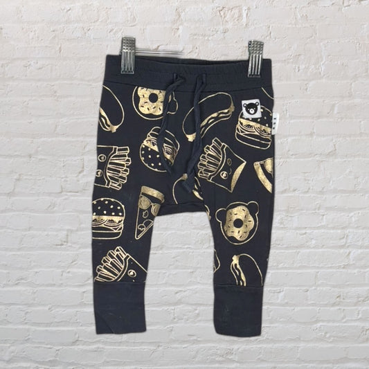 Black baby jogger pants with gold food print, including fries, burgers, and donuts, hanging on clips.