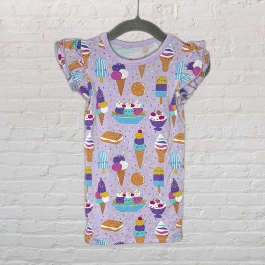 Lavender dress with ruffle sleeves featuring a colorful ice cream and dessert pattern, hanging on a dark hanger against a brick wall.